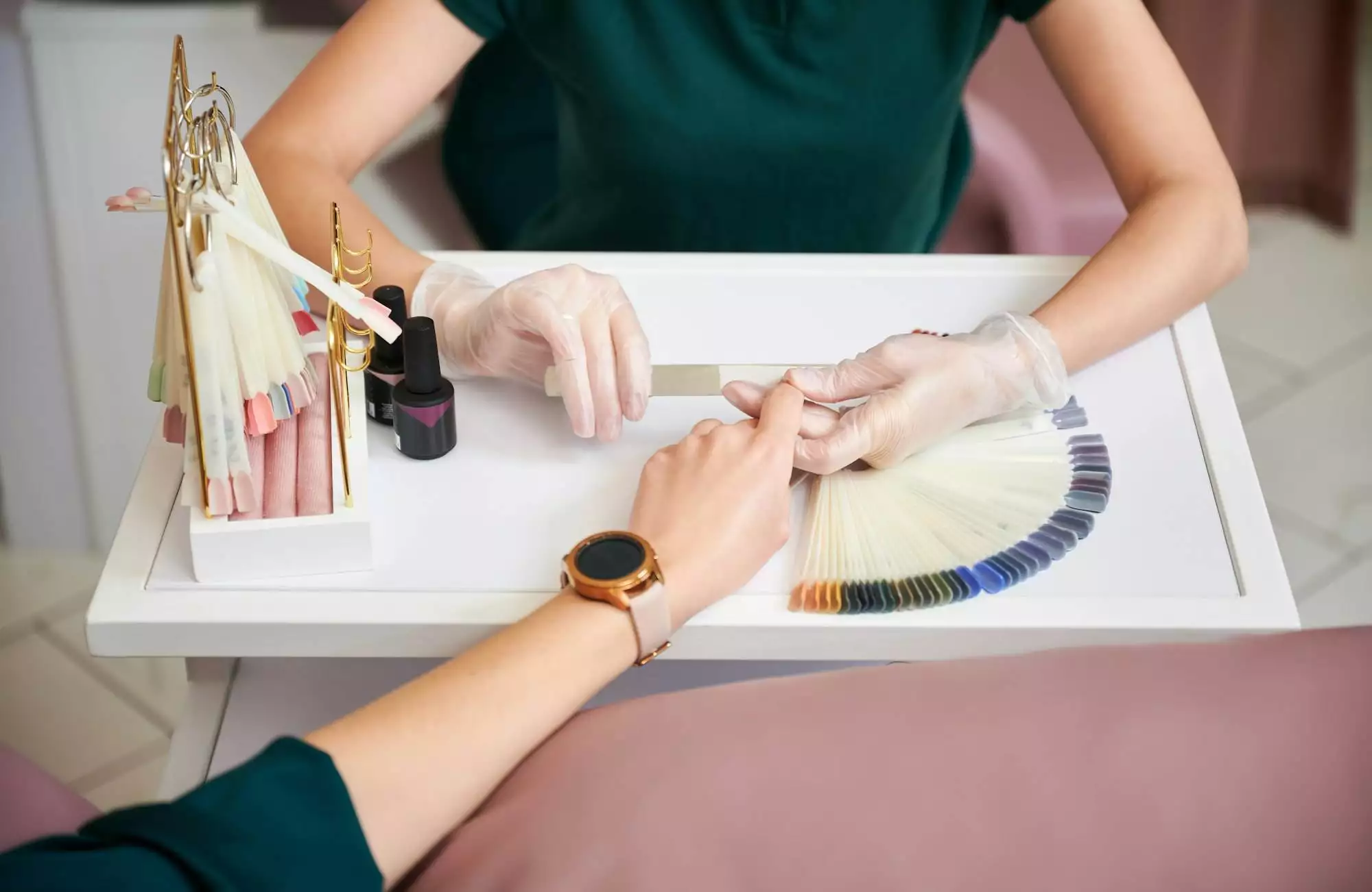 Manicurist filing woman nails with emery board in beauty salon.